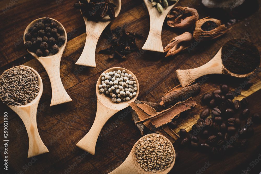 Assorted spices in wooden scoops on table