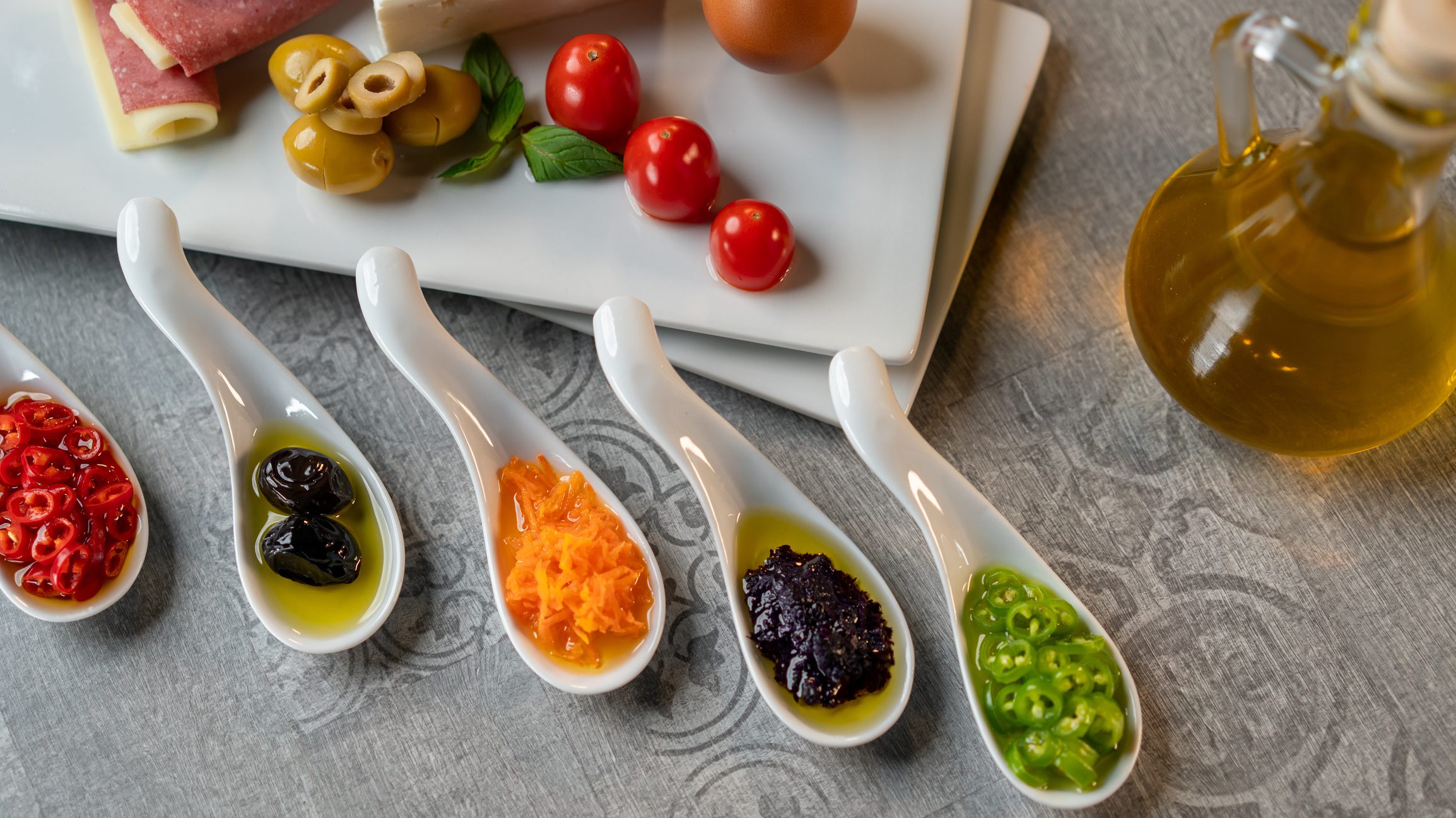 Ceramic spoons with assorted condiments and olive oil